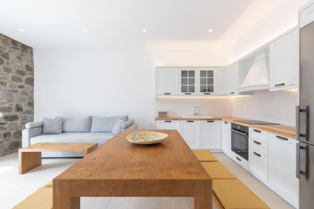 a kitchen and living room with a wooden table at ĪKADE Mykonos in Mýkonos City