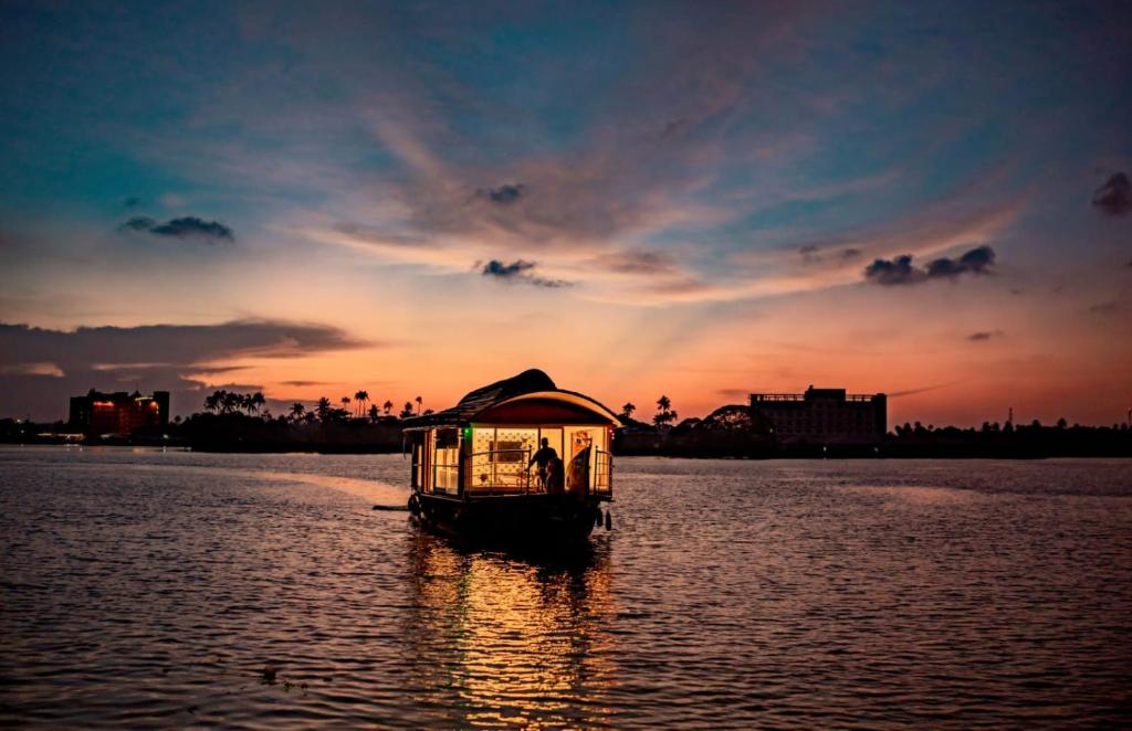 un pequeño barco en el agua al atardecer en Alice Houseboats Alleppey en Alleppey