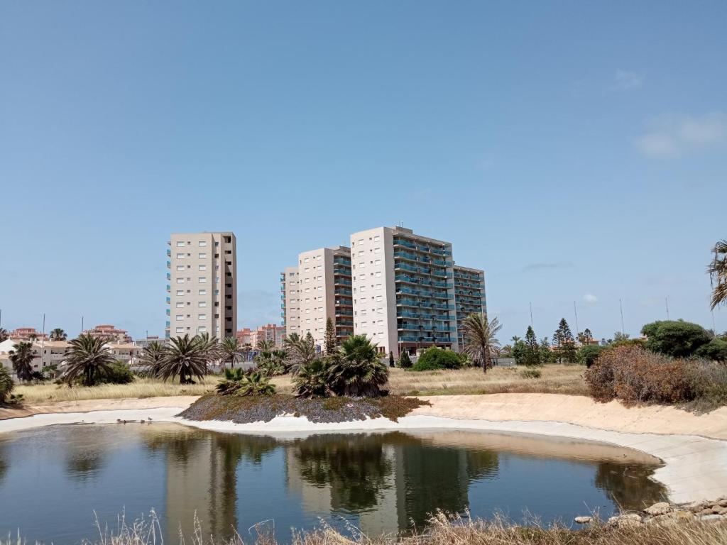 einen Teich am Strand mit Gebäuden im Hintergrund in der Unterkunft VENEZIOLA TRAVEL, relax & beach in La Manga del Mar Menor