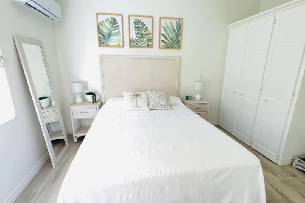 a white bedroom with a large bed and a mirror at Modern 1 Bedroom Apartment - 3 min walk to beach in Saint James