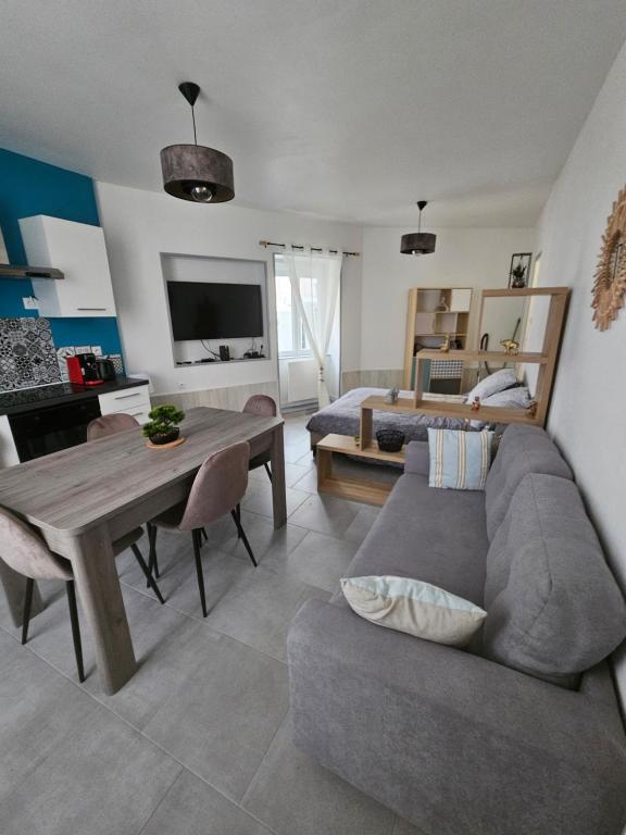 Una sala de estar con un sofá, una mesa y una cama. en Sarl la famille 2, en Angulema