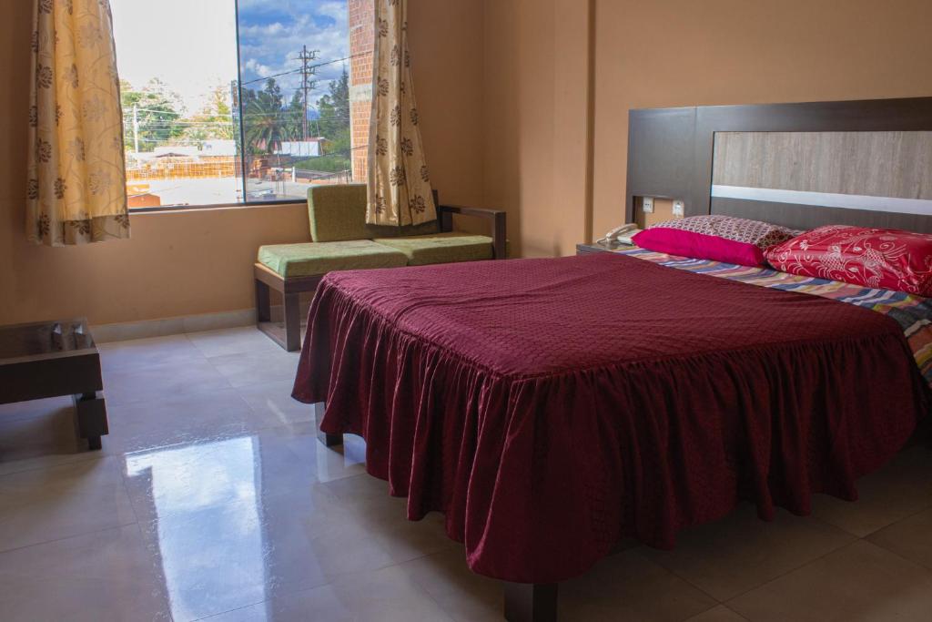 a bedroom with a large bed with a red blanket at Residencial Tablada in Tarija