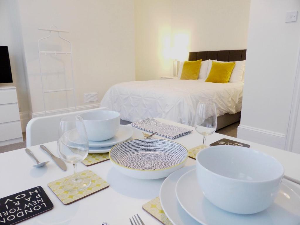 Biały stół z talerzami i okularami oraz łóżko w obiekcie Stylish studio apartment in central Hove. w Brighton and Hove