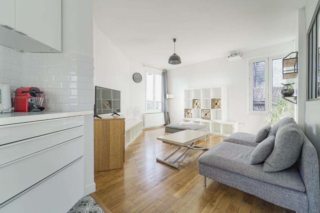 uma sala de estar com um sofá e uma mesa em Quiet cosy and large apartment with Terrace Top location em Saint-Ouen
