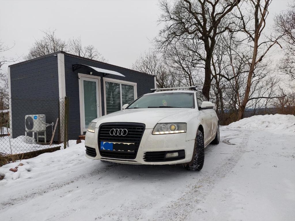 une voiture garée dans la neige devant une maison dans l'établissement Gravas mala, à Sigulda