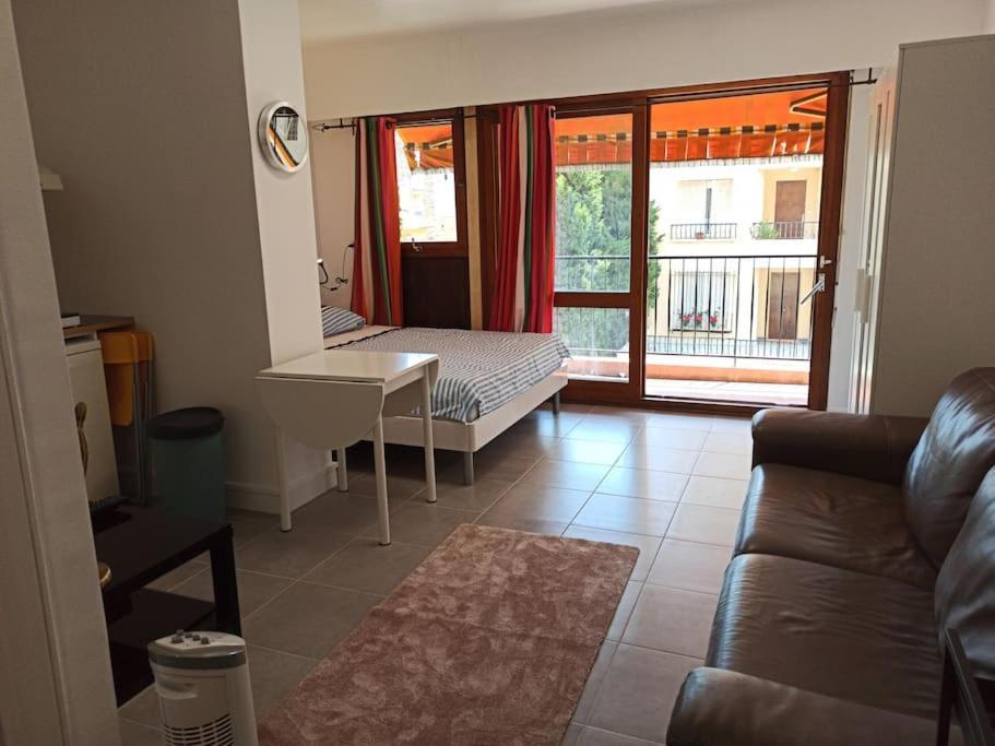een woonkamer met een bank, een bed en een raam bij Studio 4 pers, terrasse, clim, parking privé inclus in Cannes