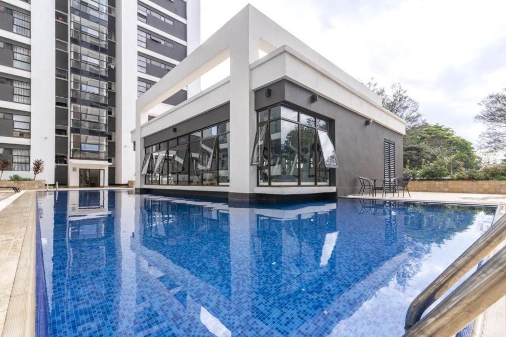 um edifício com uma grande piscina em frente a um edifício em Astoria Luxury Apartments, Lavington em Nairobi