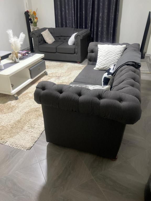 un sofá negro sentado en una sala de estar en Trisha, en Bungoma