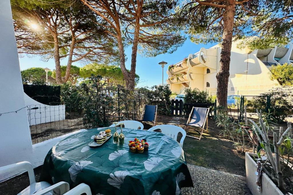 une table avec un chiffon bleu et des chaises blanches dans l'établissement LE SANTA MARIA- Appartement Une chambre avec Jardin et parking, au Grau-du-Roi