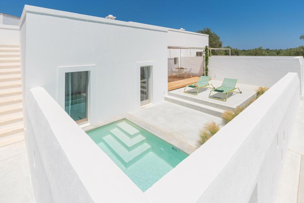 Casa blanca con piscina y 2 sillas en Masseria Pensato, en Savelletri di Fasano