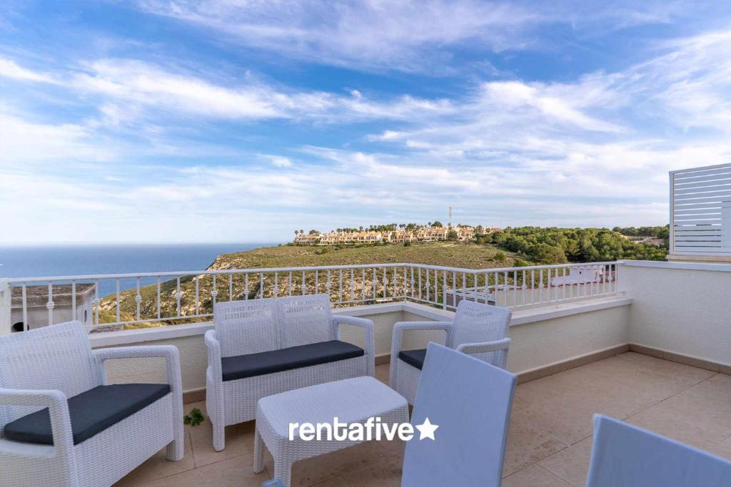 Un balcón con sillas blancas y vistas al océano. en rentafive Nuevo AA Reformado Piscina en Gran Alacant