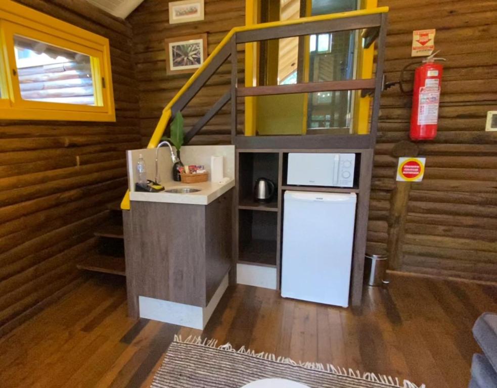 una pequeña cocina en una cabaña de madera con nevera en Refúgio Ecológico Pedra Afiada en Praia Grande