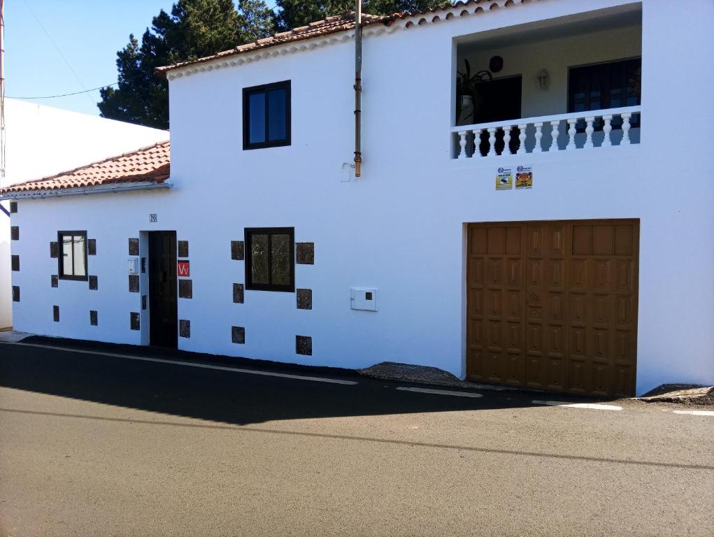 a white house with brown doors on a street at LA CASA DE PÁ in Vega de San Mateo
