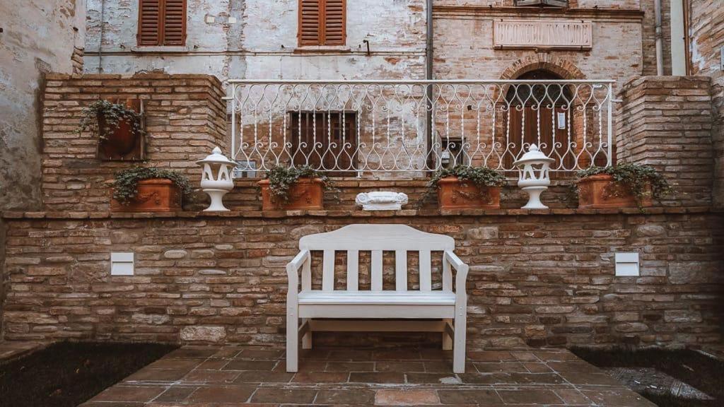 a white bench sitting in front of a brick wall at Casa Tarducci in Urbania