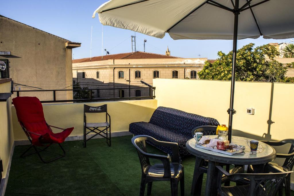 une terrasse avec une table, des chaises et un parasol dans l'établissement B&B Porta Nuova, à Palerme