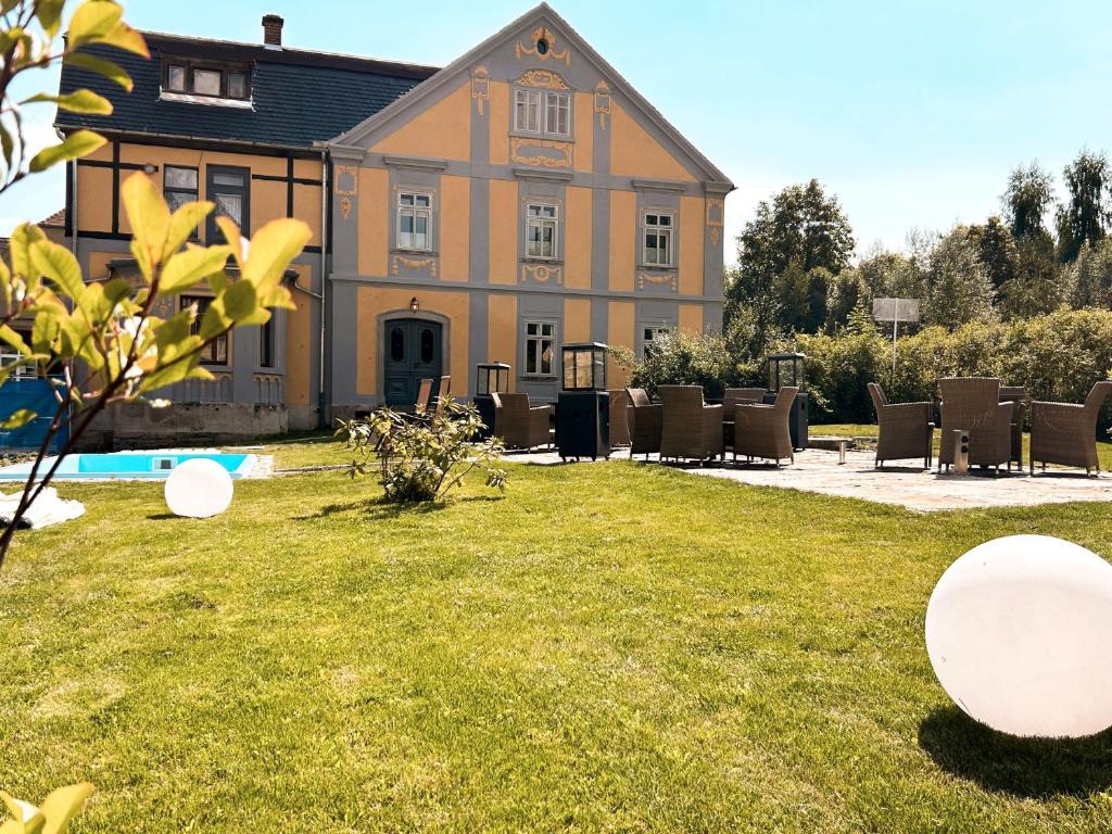 a building with a yard with chairs and a pool at Villa Hänsch Suite 3 in Großschönau
