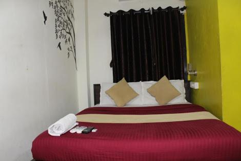 a bedroom with a large red bed with two phones on it at Hotel saffron inn in Mumbai