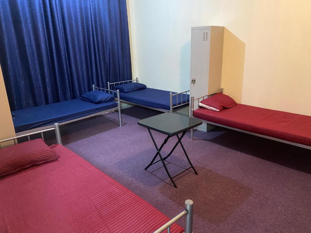 Dream valley hostel في أبوظبي: ثلاثة أسرة في غرفة مع ستائر زرقاء وطاولة