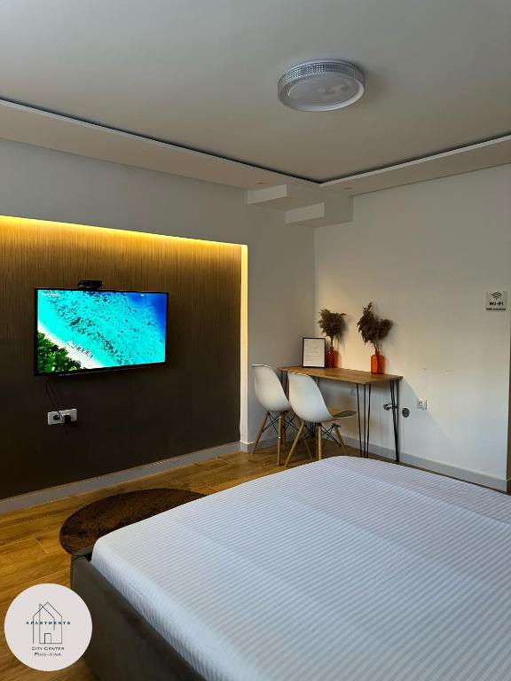 een slaapkamer met een bed en een televisie aan de muur bij Prishtina Center Apartment 3 in Pristina