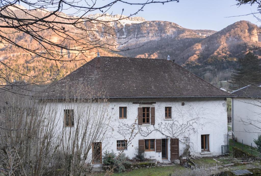 ein altes weißes Haus mit Bergen im Hintergrund in der Unterkunft Gite aux 1000 chemins - Apt 50m2 in Saint-Joseph-de-Rivière