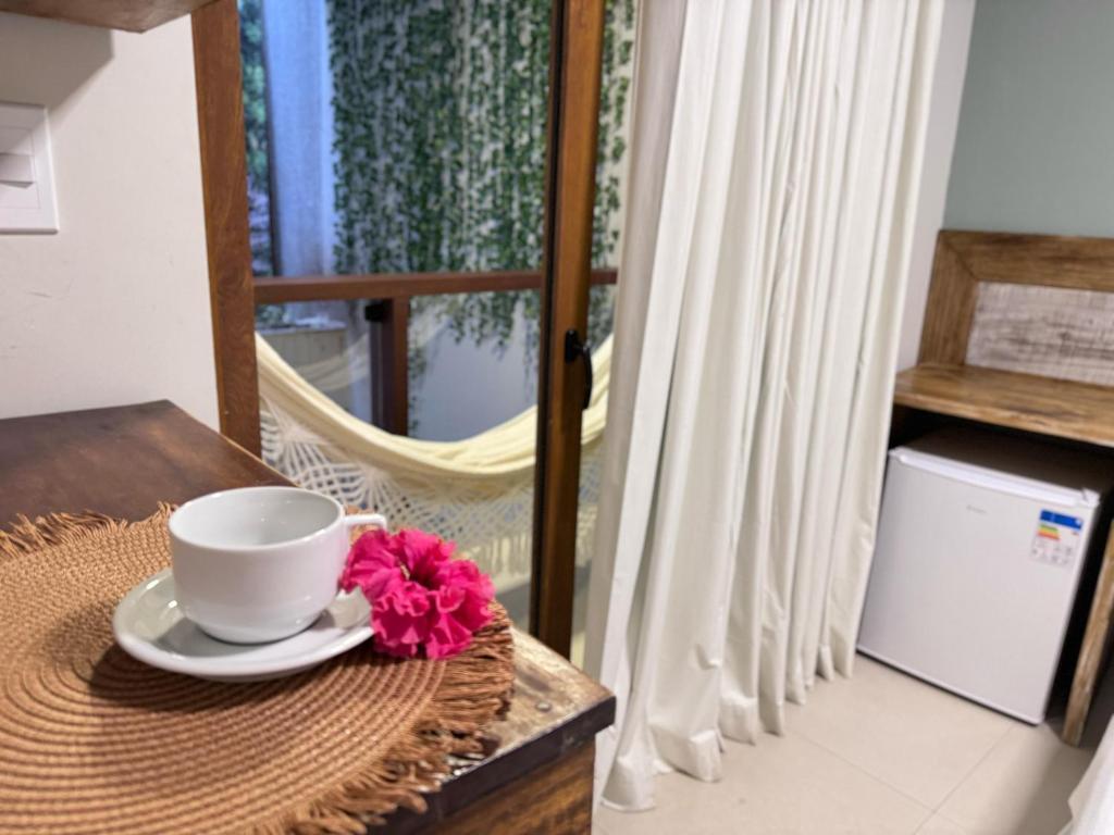 a coffee cup on a table with a flower on it at Terra Bella Pousada in Morro de São Paulo