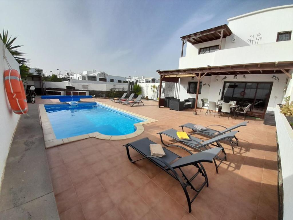 een patio met stoelen en een zwembad bij Dias Felices in Playa Blanca