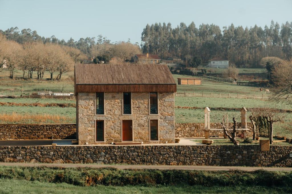un pequeño edificio con una pared de piedra en un campo en A casa de Foratoxo, en A Bana
