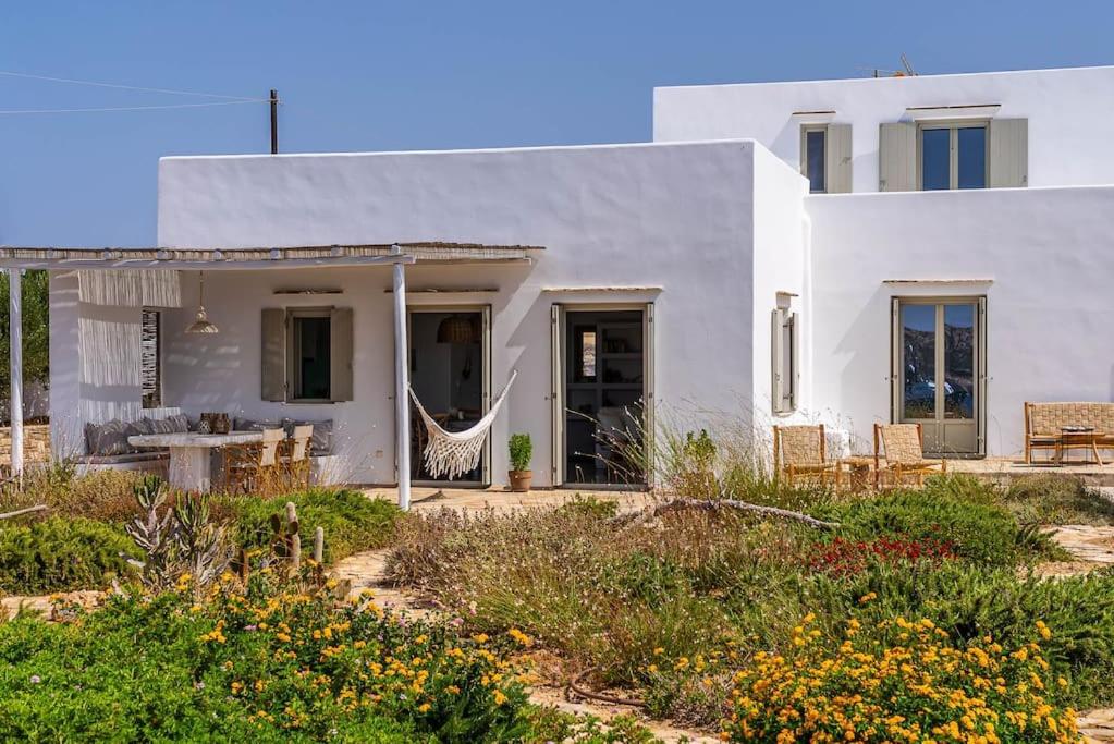 a white house with a garden in front of it at House of Harmony - Beachfront in Antiparos