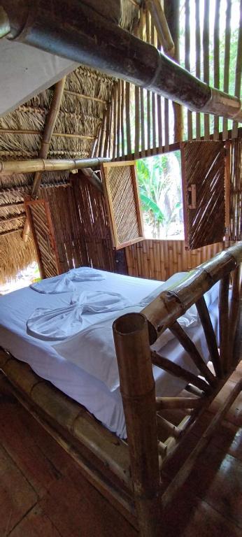 a bed in a thatched room with a bedsheet at Polvo en el Aire in Santo Domingo