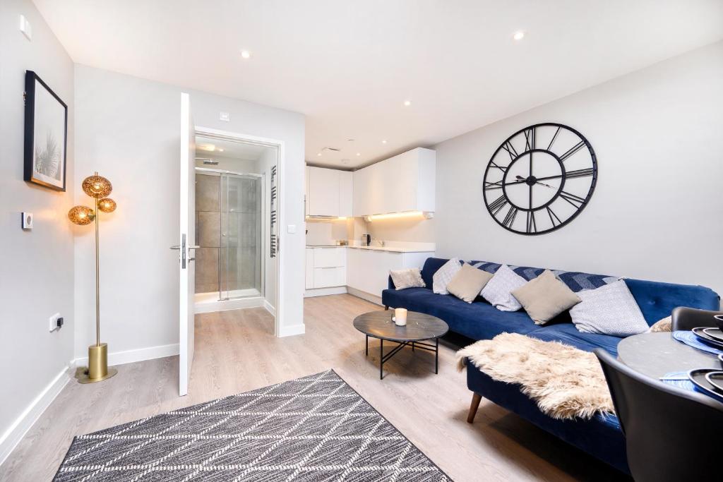 a living room with a blue couch and a clock on the wall at New Modern 1 Bed Flat Great Location Piccadilly Line in Hounslow