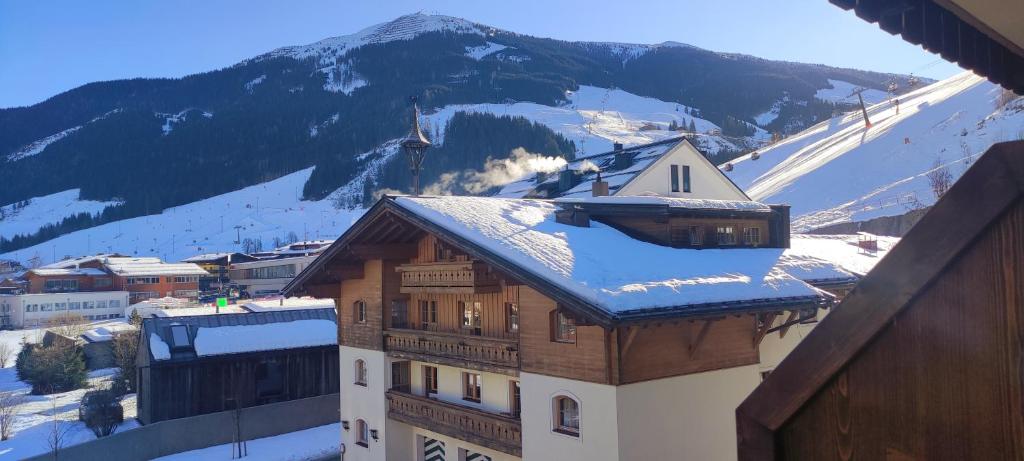 a building with snow on the roof with a mountain at Next to Zwölferkogel - include Jokercard - only summer in Saalbach Hinterglemm