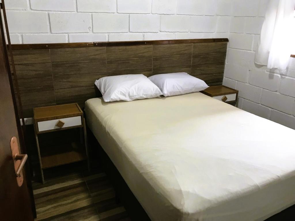 Una cama con dos almohadas blancas encima. en Villaggio Miravela en Caraguatatuba