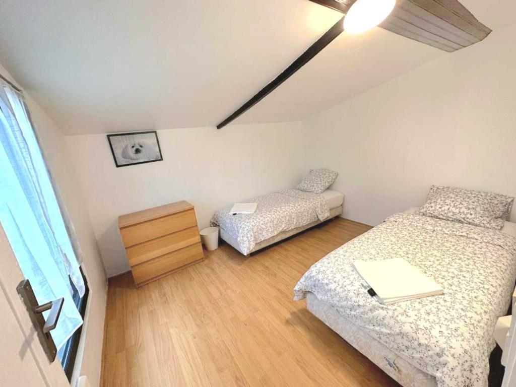 ein kleines Zimmer mit 2 Betten und einer Kommode darin in der Unterkunft L'adorable Maison des Clients 15min de Paris in Houilles
