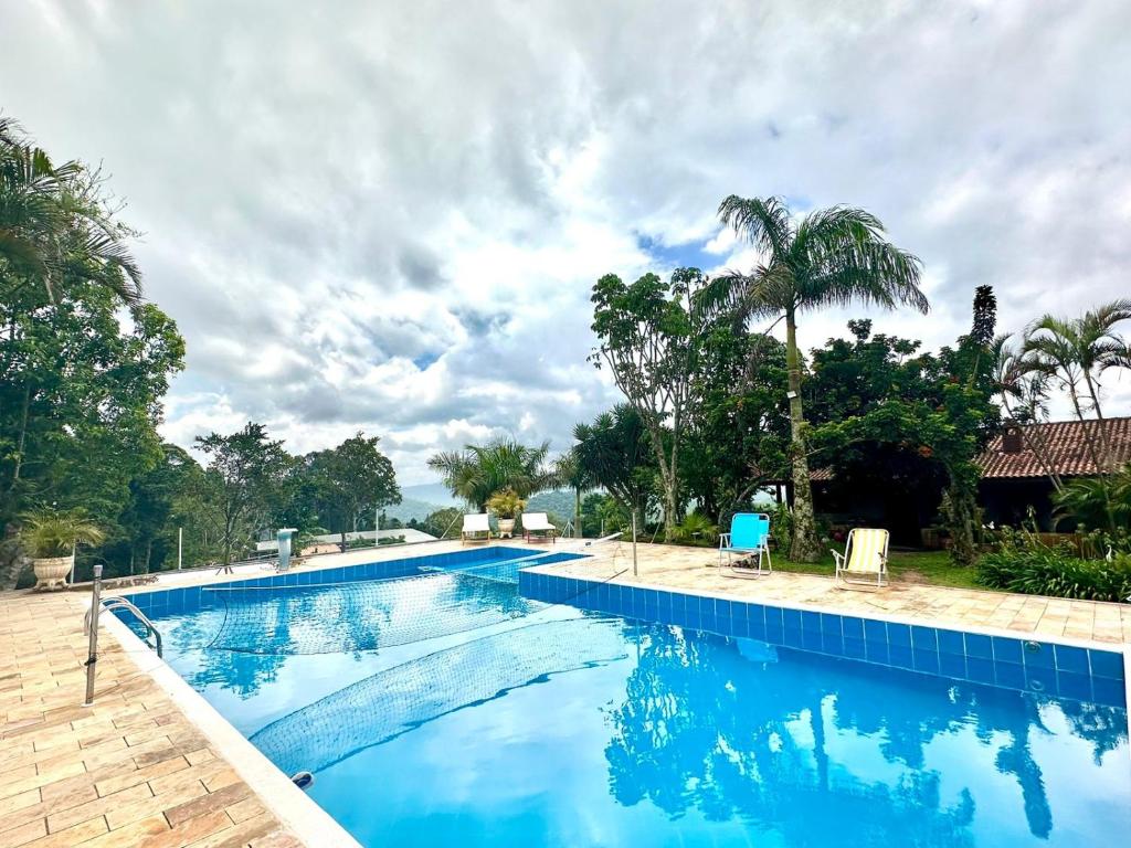 a swimming pool with blue water and palm trees at Rancho NPI in Guarulhos