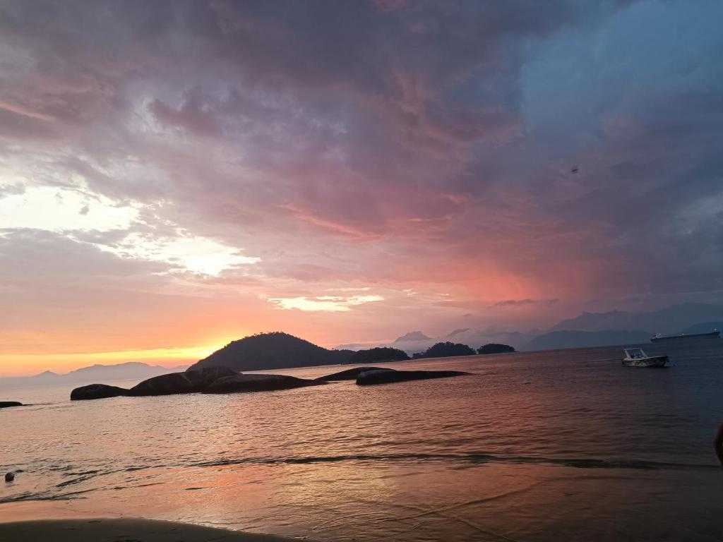 - un coucher de soleil sur la plage avec un bateau dans l'eau dans l'établissement Por do sol Jaguanum, à Mangaratiba