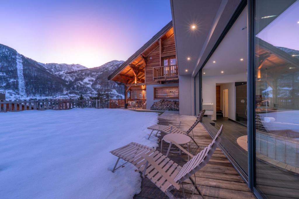 une terrasse avec des chaises, un bain à remous et des montagnes dans l'établissement Chalet Snowbird 5 étoiles, Serre-Chevalier, à La Salle Les Alpes