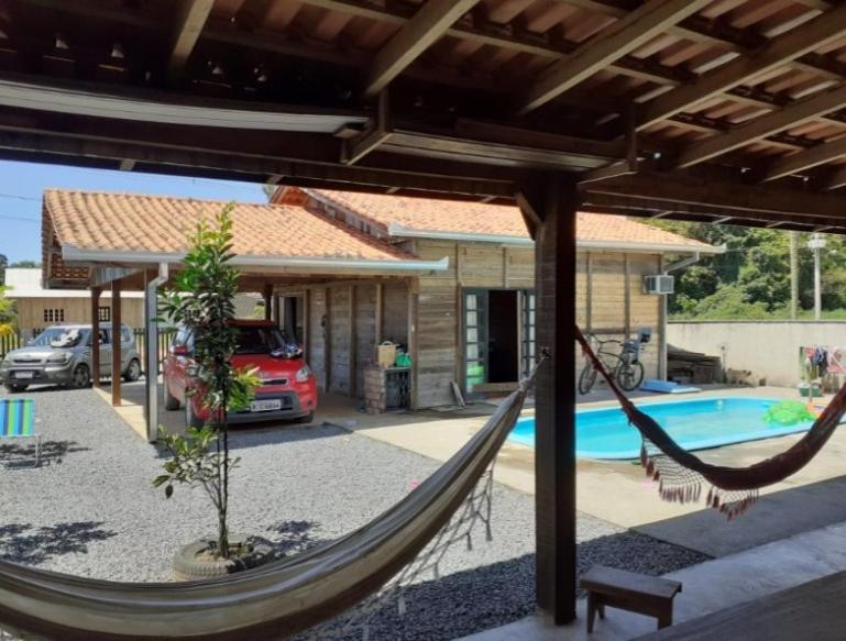 a hammock in front of a house with a pool at CASA DE VERANEIO COM PISCINA in São Francisco do Sul