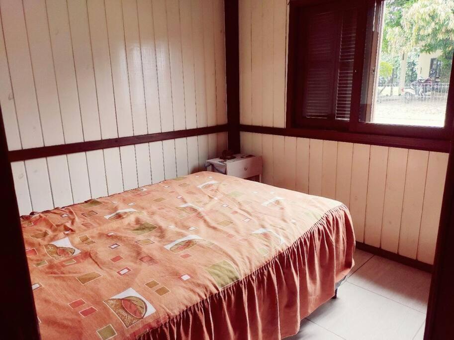 a bedroom with a bed with a blanket on it at Aluguel casa temporada praia do rosa in Garopaba