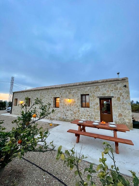 a picnic table in front of a stone building at Mas de Melonet Delta del Ebro in L'Aldea