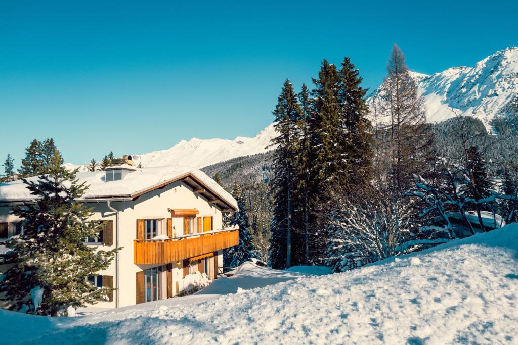 a house in the snow with mountains in the background at Casa Nonna in Lenzerheide