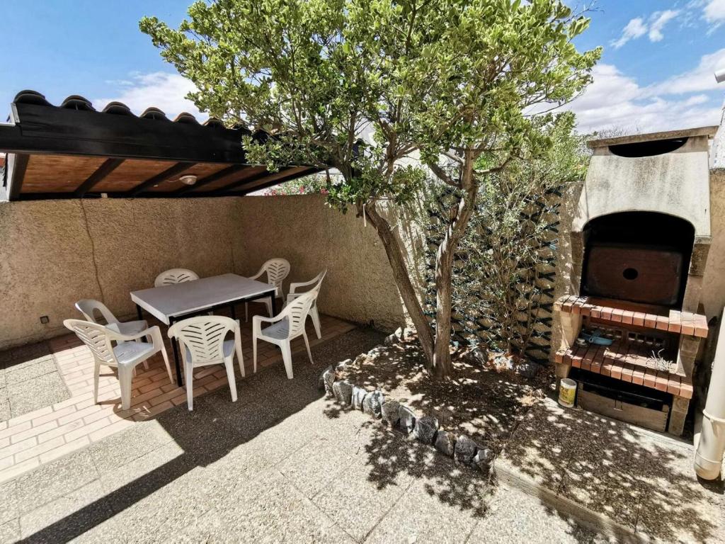 d'une terrasse avec une table, des chaises et un arbre. dans l'établissement Résidence Le Village Grec - VILLA 4 PIECES 6 couchages PORT LEUCATE MAE-6964, à Port-Leucate