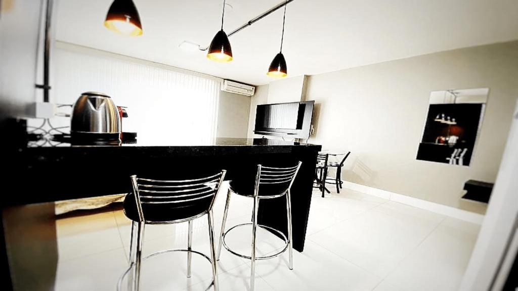 a kitchen with a bar with two stools in it at 105 Saint Sebastian Flat in Jaraguá do Sul