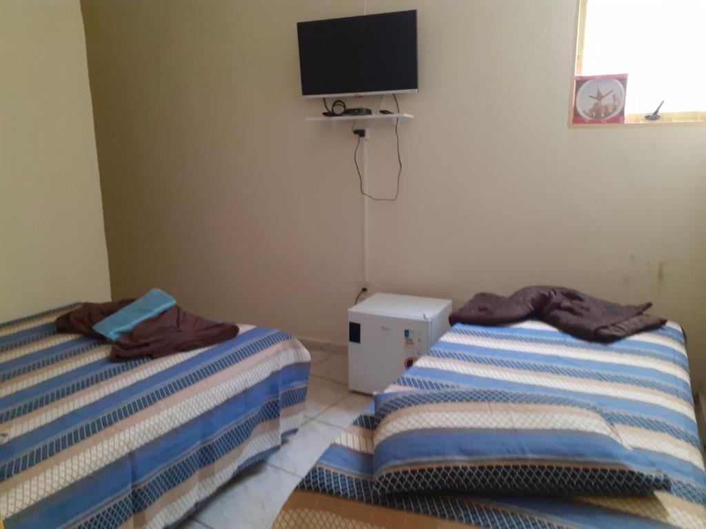 2 camas en una habitación con TV en la pared en Espaço antonela e Ana livia, en Aparecida