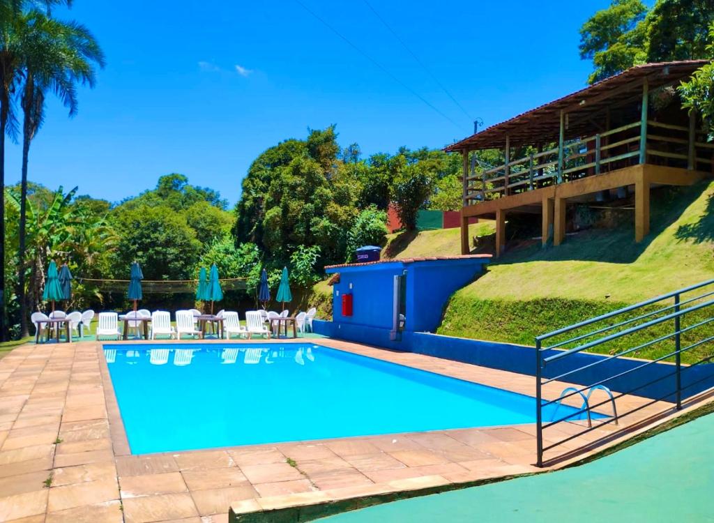 una piscina en un complejo con sillas y un edificio en Pousada Recanto do Chalé Ltda en Macacos