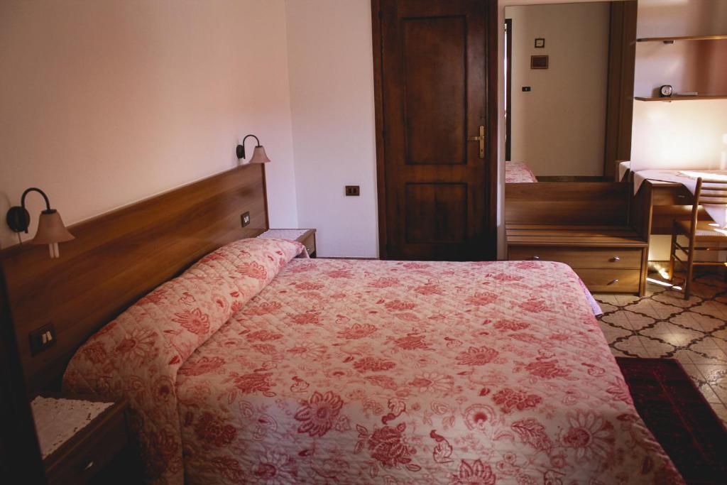 Agriturismo Perdaba في فلومينيماجيوري: غرفة نوم بسرير ولحاف ورد احمر