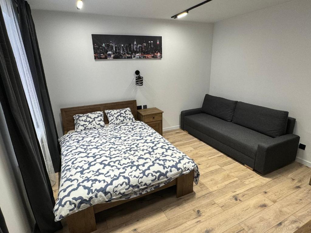 a bedroom with a bed and a couch at Brooklyn Apartaments z Konsola X Box plus parking in Katowice