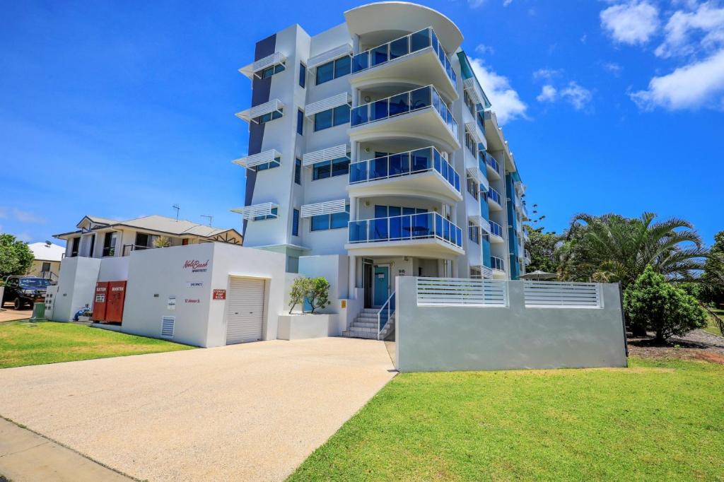 a large white apartment building with blue balconies at Ohana Vibe Bargara in Bargara