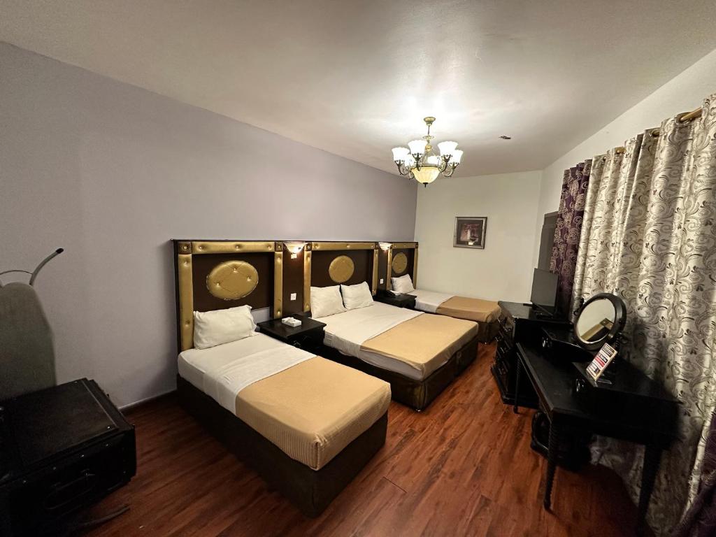 a hotel room with two beds and a mirror at Hafez Hotel Apartments in Dubai