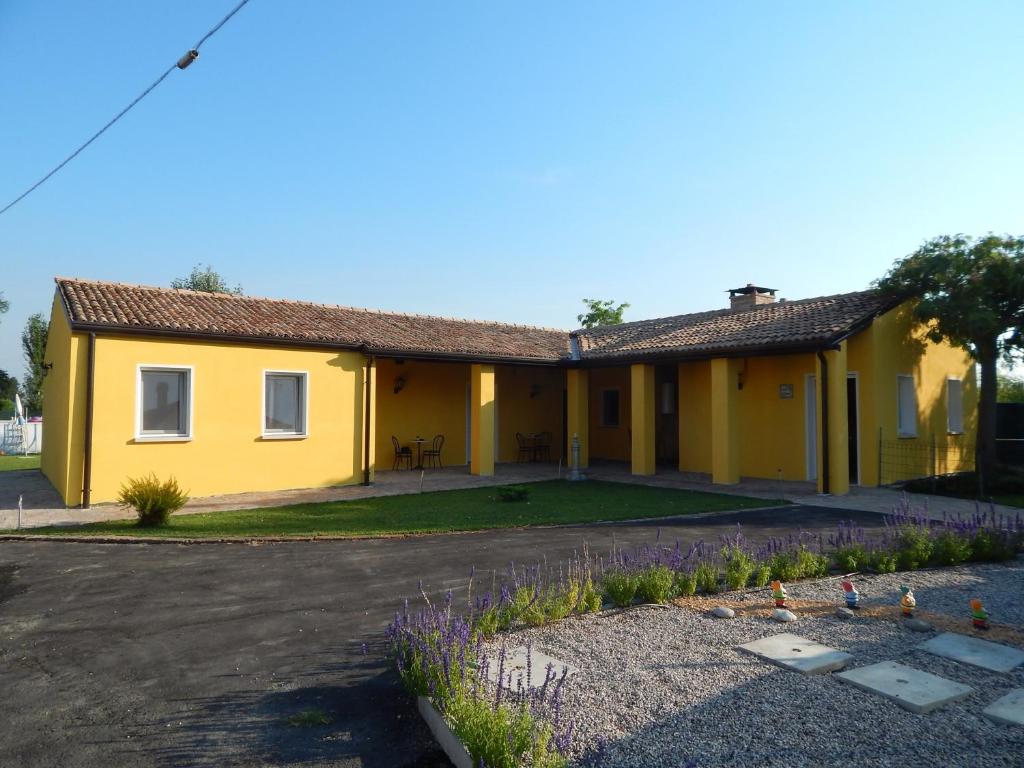 a yellow house with a yard at B&B Corte Bolandina in Taglio di Po