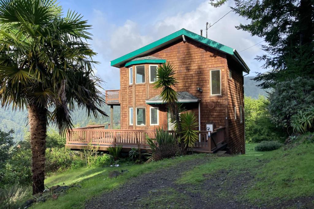 Casa de madera con techo verde y palmera en Ocean View Getaway, en Shelter Cove